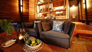 Una sala acogedora con un sofá, una mesa de centro con frutas y una vela, y una estantería de madera.