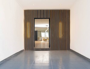 Ein Flur mit modernem Design, der sich durch eine Wand aus Holzlamellen und einen Fliesenboden auszeichnet.