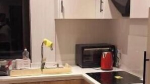 Een moderne keuken met houten kastjes, een magnetron en een spoelbak.