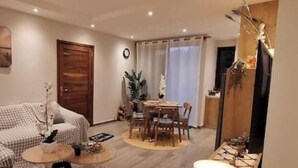 Een woonkamer met een bank, een salontafel en een eethoek met een tafel en stoelen.