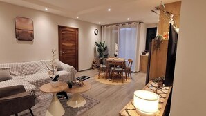 Een woonkamer met een bank, salontafel en een eethoek met stoelen.
