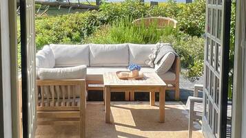 An open patio with a sofa, chairs, and a table, overlooking a natural landscape.