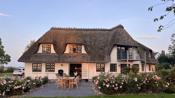 A thatched-roof house with a patio and outdoor seating area.