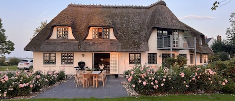 A thatched-roof house with a patio and outdoor seating area.