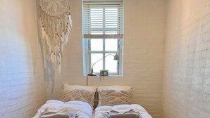 A bedroom with a bed, a window, and a wall decoration.