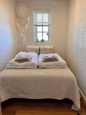 A bedroom with a bed, a window, and a wall decoration.