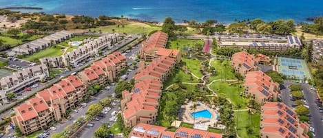 A resort with multiple buildings, a swimming pool, and a view of the ocean.