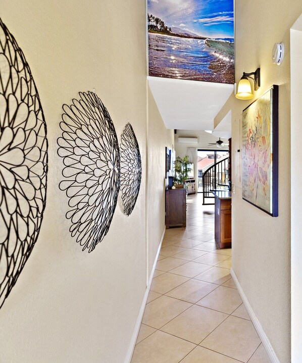 Un couloir orné d’une grande fresque murale, doté d’un luminaire fixé au plafond et offrant une vue sur un espace repas.