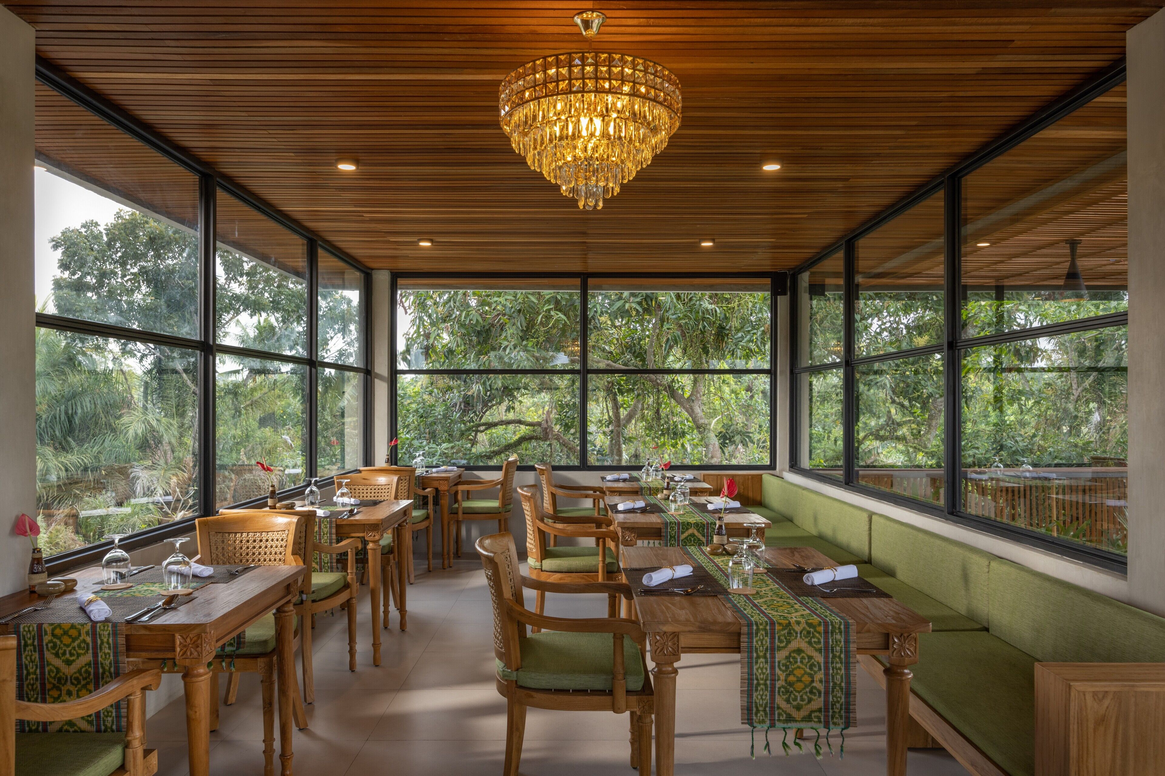 A restaurant with wooden furniture, large windows, and a chandelier.