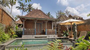 Un bâtiment traditionnel avec un toit en tuiles, une piscine et une végétation tropicale luxuriante.