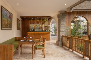 A hotel lobby with a bar area, seating, and a view of the outdoors.