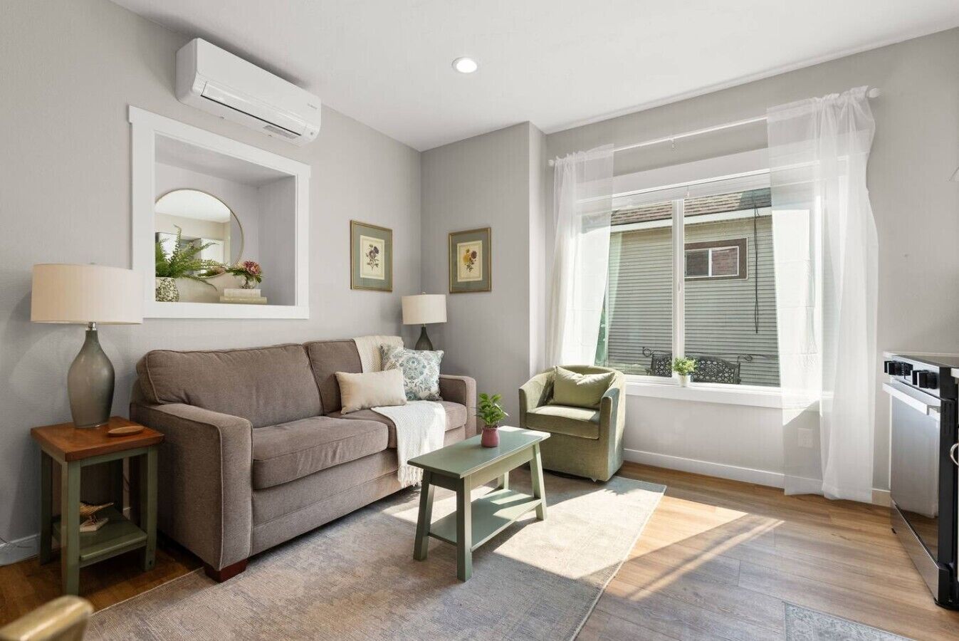 A living room with a sofa, armchair, small table, and a window with curtains.
