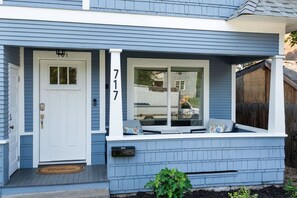 A residential house with a white door, a mailbox, and a window with a view of the backyard. - Little Garden Bungalow (Spokane)