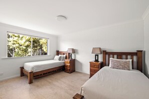 Ein Schlafzimmer mit zwei Betten, einem Fenster und einem Nachttisch mit Lampe.