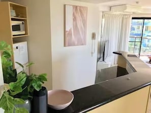 Una cocina con encimera negra, microondas y planta en maceta.