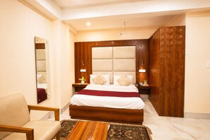 Une chambre d’hôtel avec un grand lit, une tête de lit en bois, des tables de chevet avec des lampes, une chaise et une petite table.