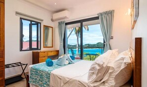 Un dormitorio con cama, escritorio y vista al mar.