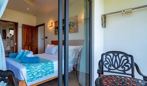 A bedroom with a bed, a chair, and a window. - CASA GEM Seychelles (Victoria)