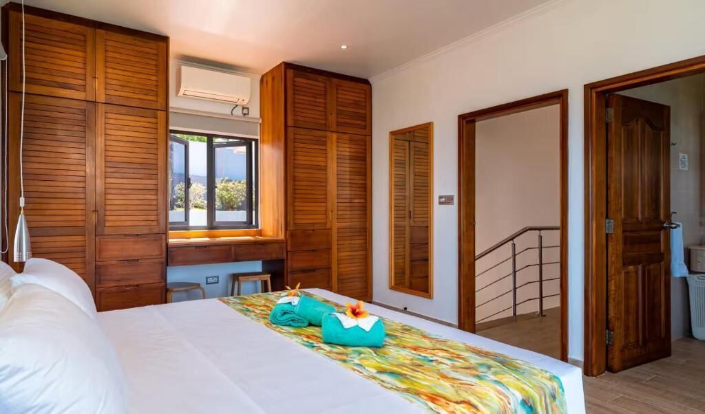 Une chambre à coucher avec un lit, une armoire en bois, un bureau et une fenêtre.