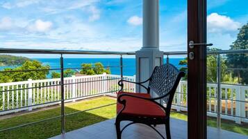 Ein Balkon mit Blick aufs Meer, ein weißer Zaun und ein roter Stuhl.