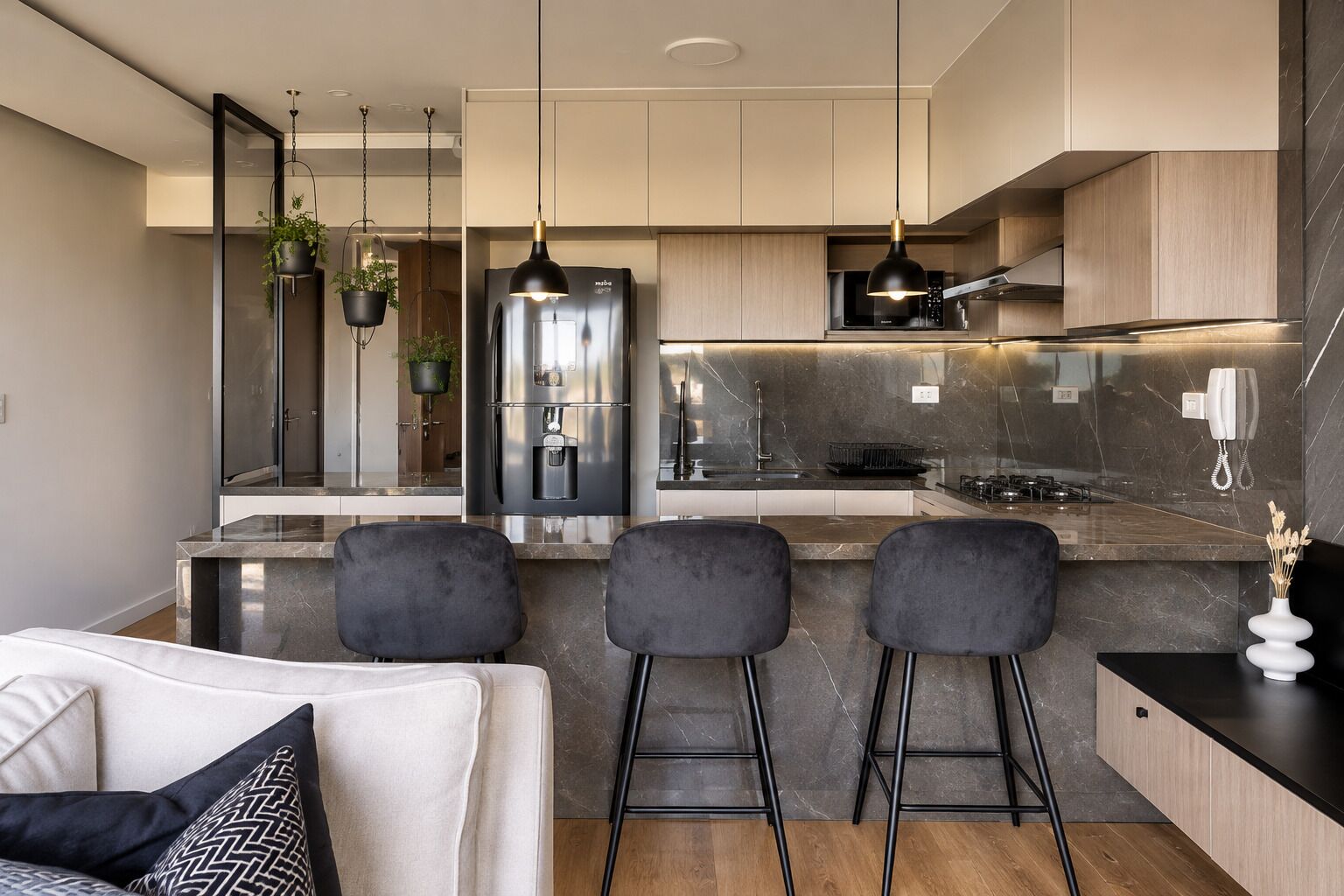 Una cocina moderna con una isla central, taburetes de bar y un horno empotrado.