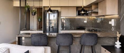 A modern kitchen with a central island, bar stools, and a built-in oven.