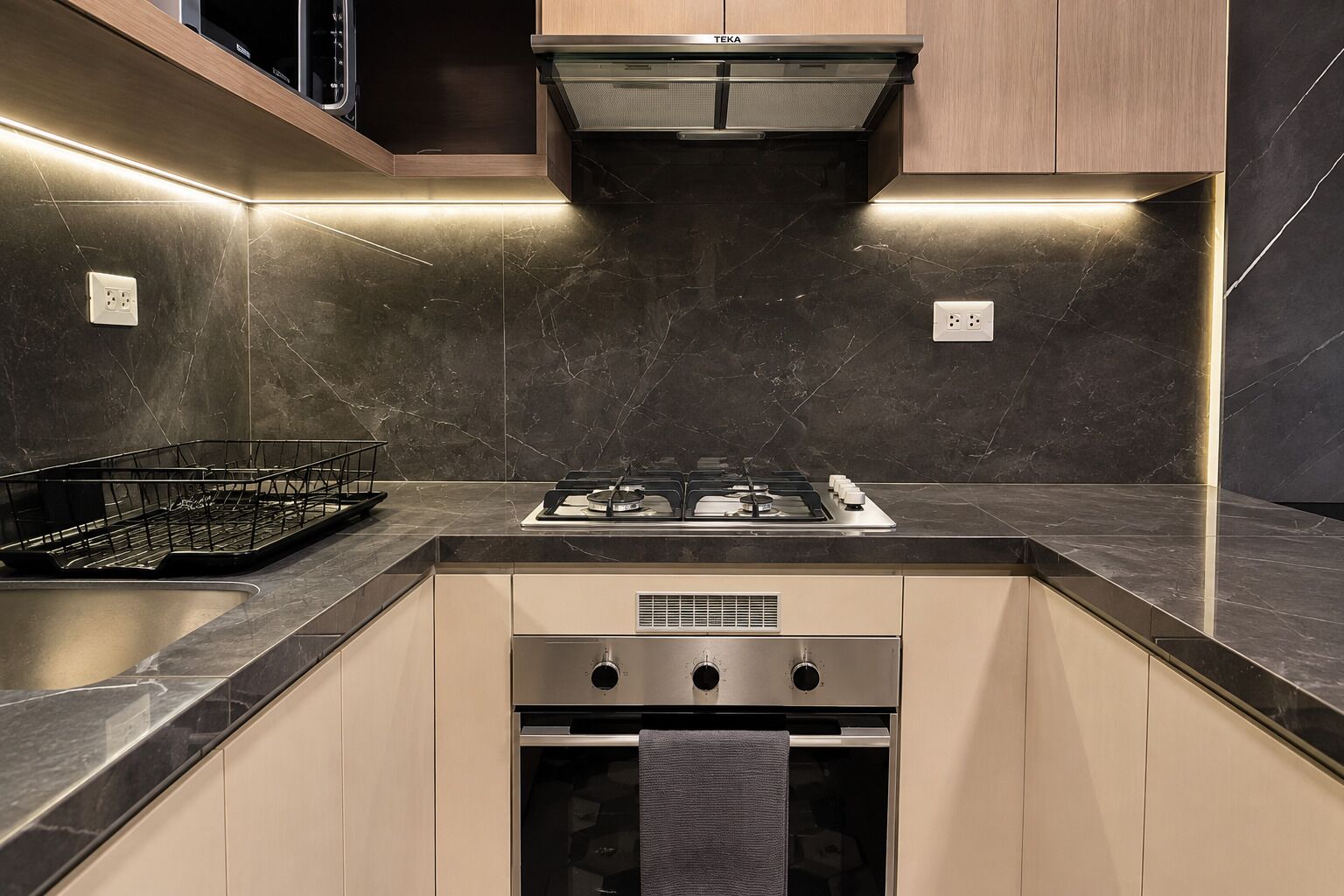 A modern kitchen with a built-in gas stove, oven, and a stainless steel range hood.