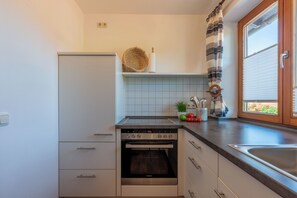 Eine moderne Küche mit Einbauofen, Spüle und Fenster mit Jalousien.