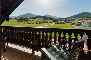 Um deck de madeira com vista para uma paisagem verde e casas.