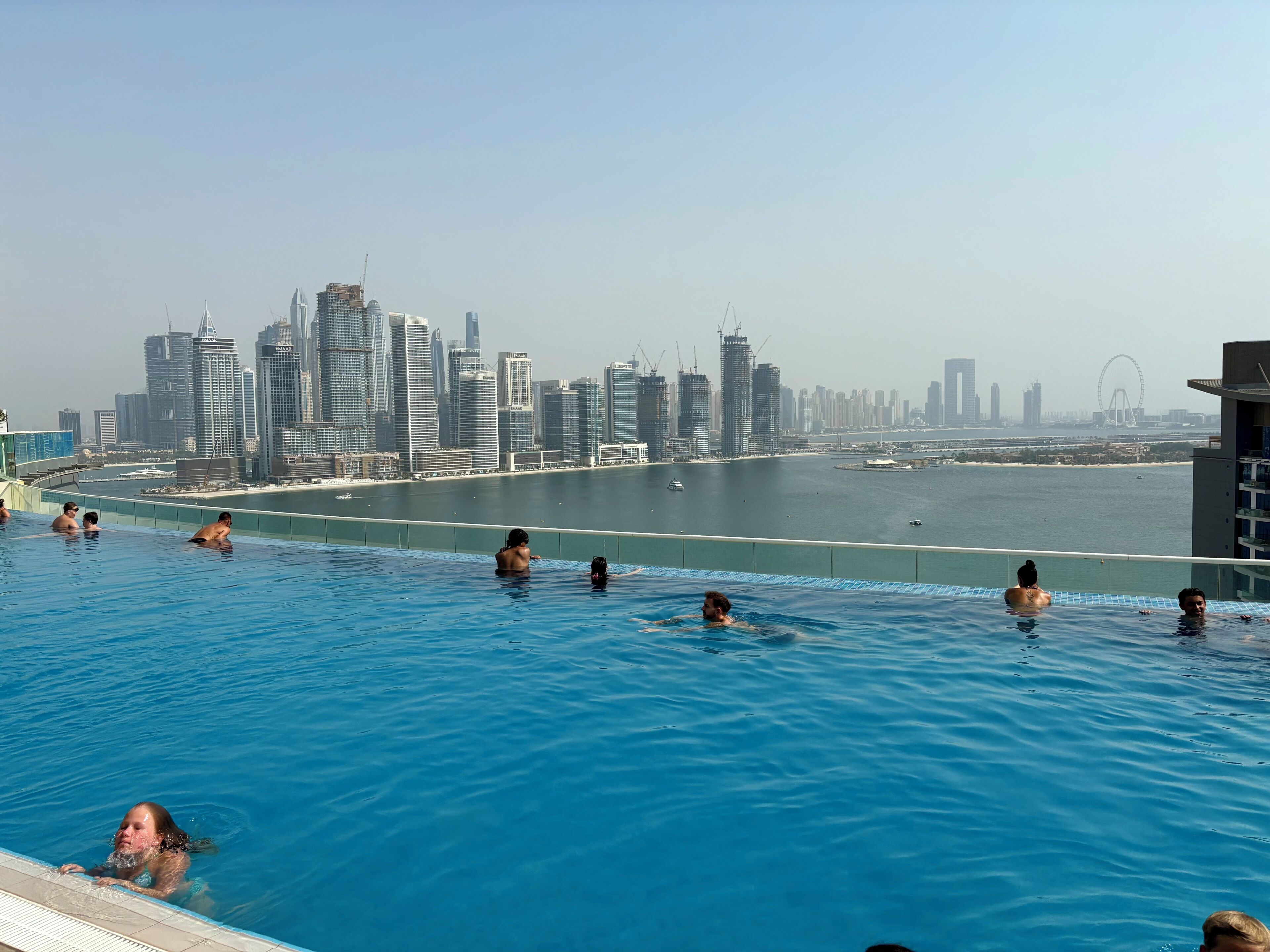 Piscina com vista para o horizonte da cidade, incluindo edifícios altos e uma roda gigante.