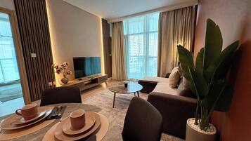 Une chambre d’hôtel moderne équipée d’un téléviseur à écran plat, d’un canapé, d’une table à manger et d’une grande plante.