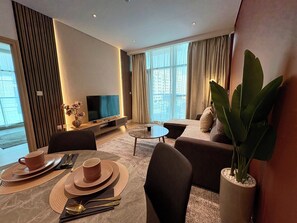 Une chambre d’hôtel moderne équipée d’un téléviseur à écran plat, d’un canapé, d’une table à manger et d’une grande plante.