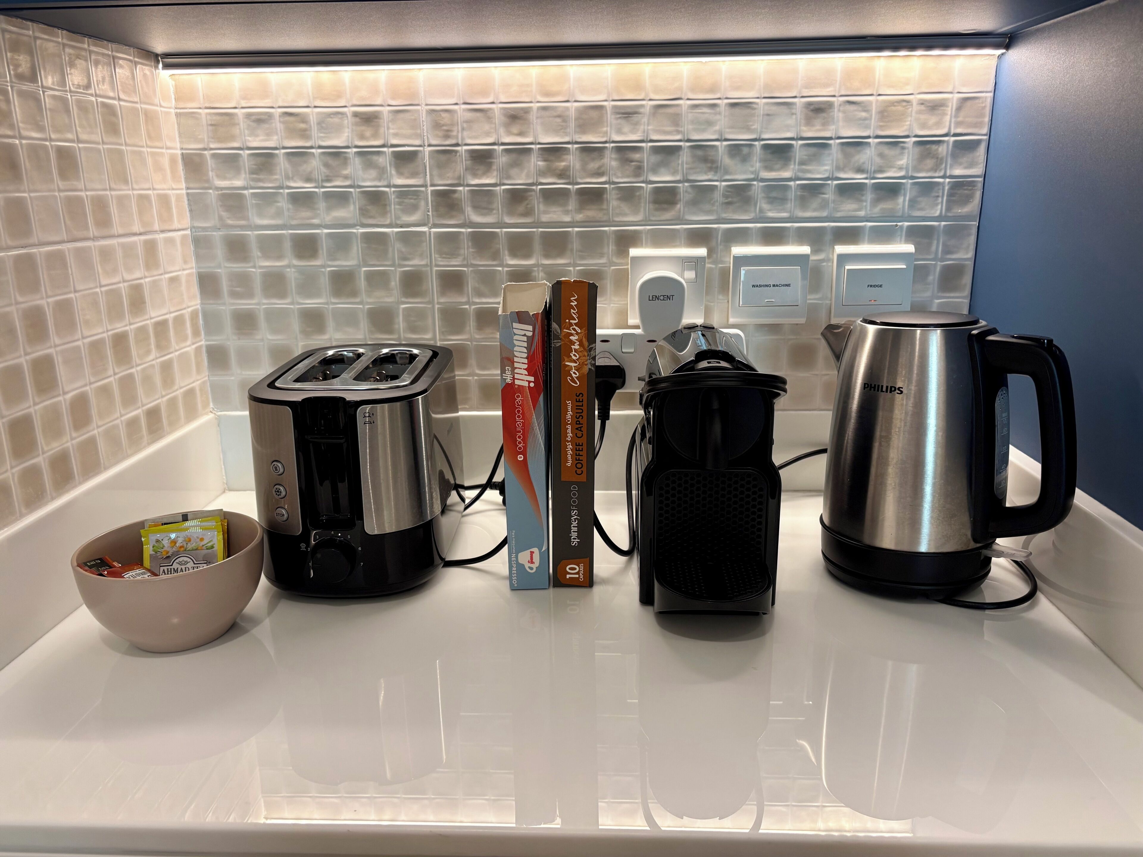 A kitchen counter with a toaster, coffee maker, kettle, and a bowl of cereal.