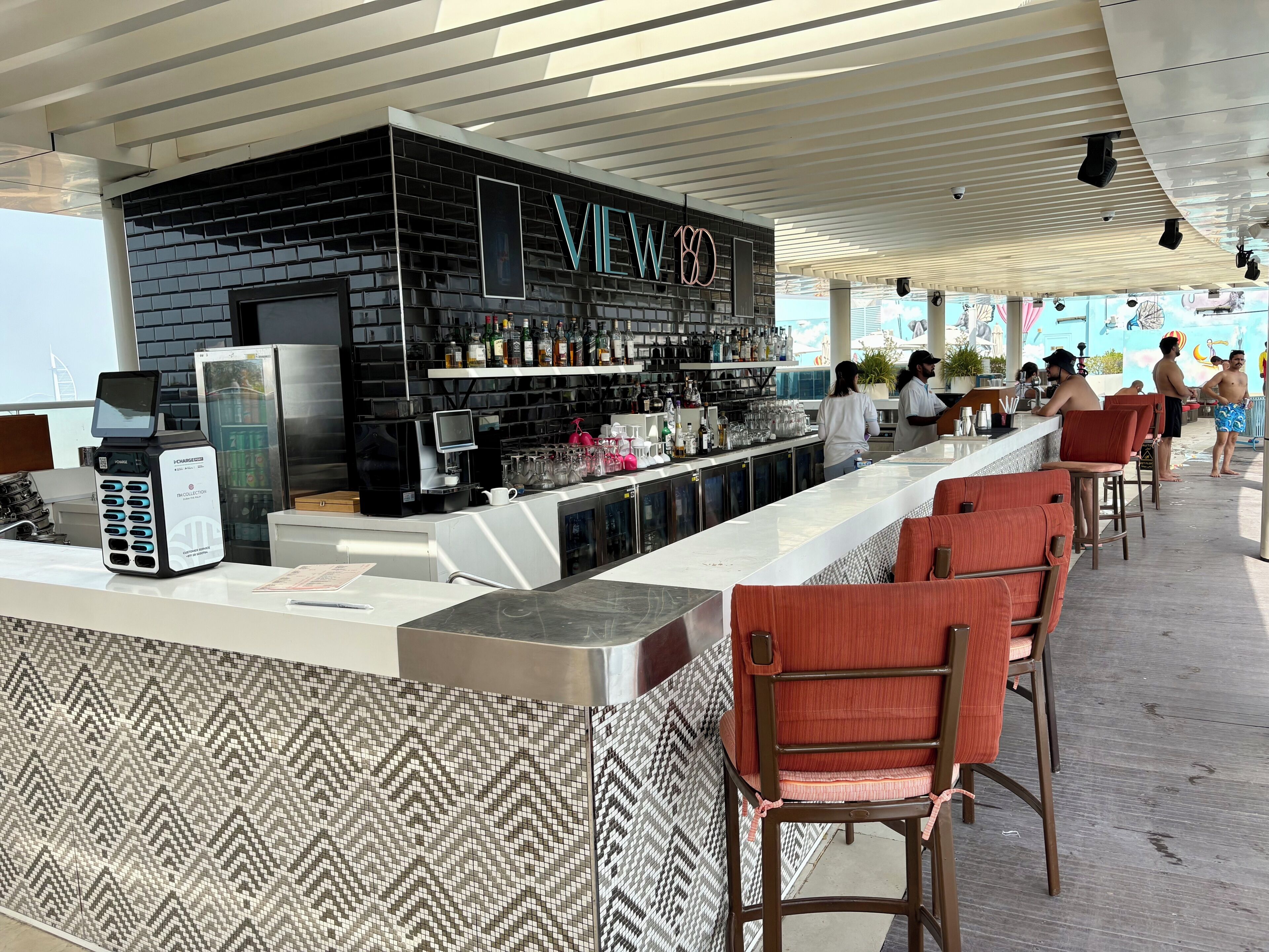 Un espace bar avec un mur en briques noires, un néon et un comptoir doté d’un terminal de paiement.