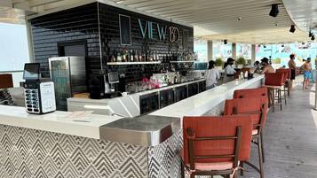 Un espace bar avec un mur en briques noires, un néon et un comptoir doté d’un terminal de paiement.