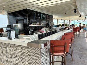Un espace bar avec un mur en briques noires, un néon et un comptoir doté d’un terminal de paiement.