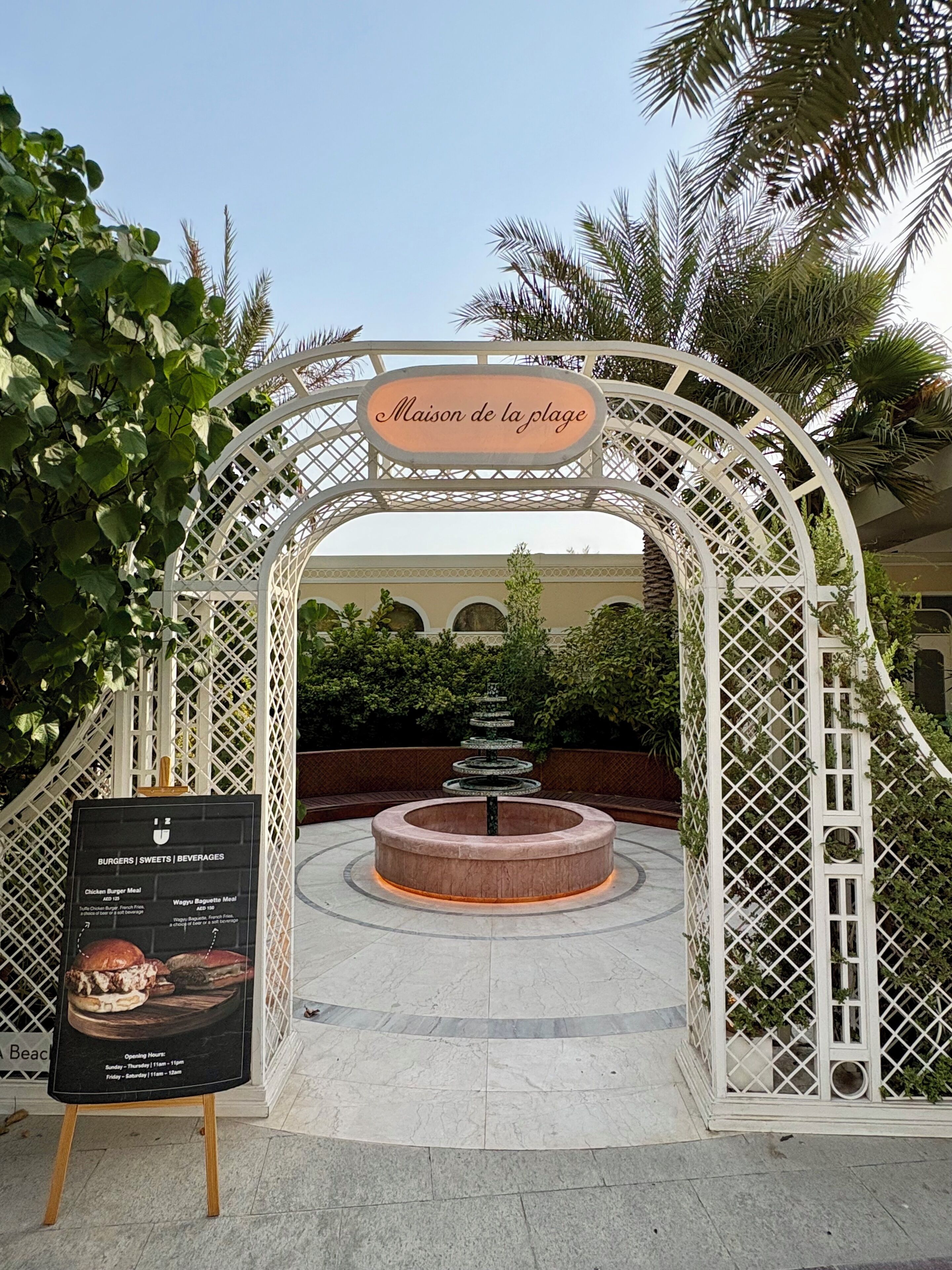 Une arche d’entrée sur laquelle on peut lire « Maison de la plage » et un panneau indiquant les différents plats et boissons proposés.