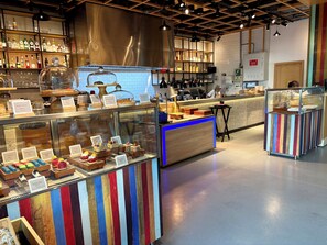 Un comptoir de boulangerie où sont exposées diverses pâtisseries, ainsi qu’un espace dédié au café.