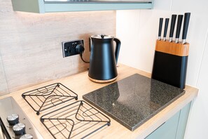 Una cocina con un hervidor negro, un bloque de cuchillos y una encimera.