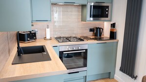 A compact kitchen with a gas stove, oven, and a microwave. - Barlocco -  a lodge that sleeps 2 guests  in 1 bedroom (Isles of Fleet Retreat, Gatehouse of Fleet)