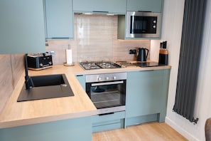 A compact kitchen with a gas stove, oven, and a microwave. - Barlocco -  a lodge that sleeps 2 guests  in 1 bedroom (Isles of Fleet Retreat, Gatehouse of Fleet)