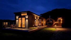 Una casa moderna con una gran estructura circular, posiblemente una sauna o jacuzzi, y una entrada bien iluminada.
