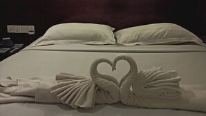 A hotel room with a bed, pillows, and a wall-mounted light fixture.
