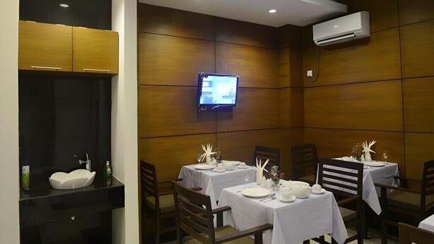 A restaurant with tables set for dining, a television mounted on the wall, and an air conditioning unit.