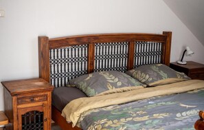 A bed with a wooden headboard, two nightstands, and a lamp on the right side.