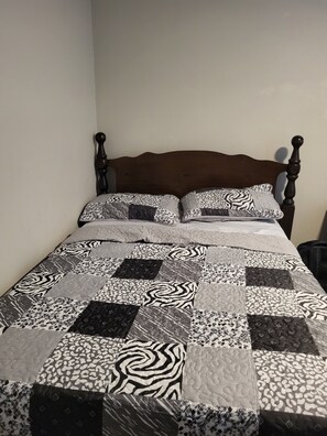 A bed with a dark wooden headboard and a quilt with various patterns. - EvidenceTouch Homes 03 (Odessa)