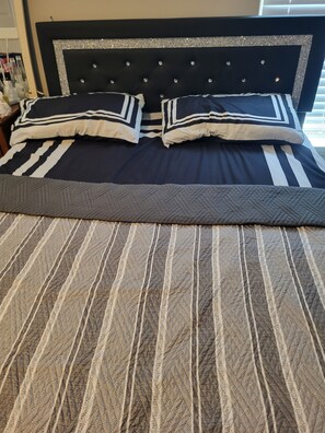 A bed with a striped bedspread and two pillows.