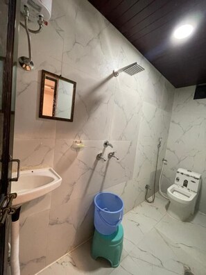 A bathroom with a sink, mirror, shower, and toilet. - HOTEL GLOBAL (Ujjain)