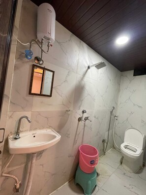 Un bany amb un lavabo, un mirall, una dutxa i un vàter.