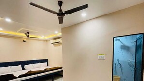 Una habitación de hotel con cama, un banco, un ventilador de techo y un espejo grande.